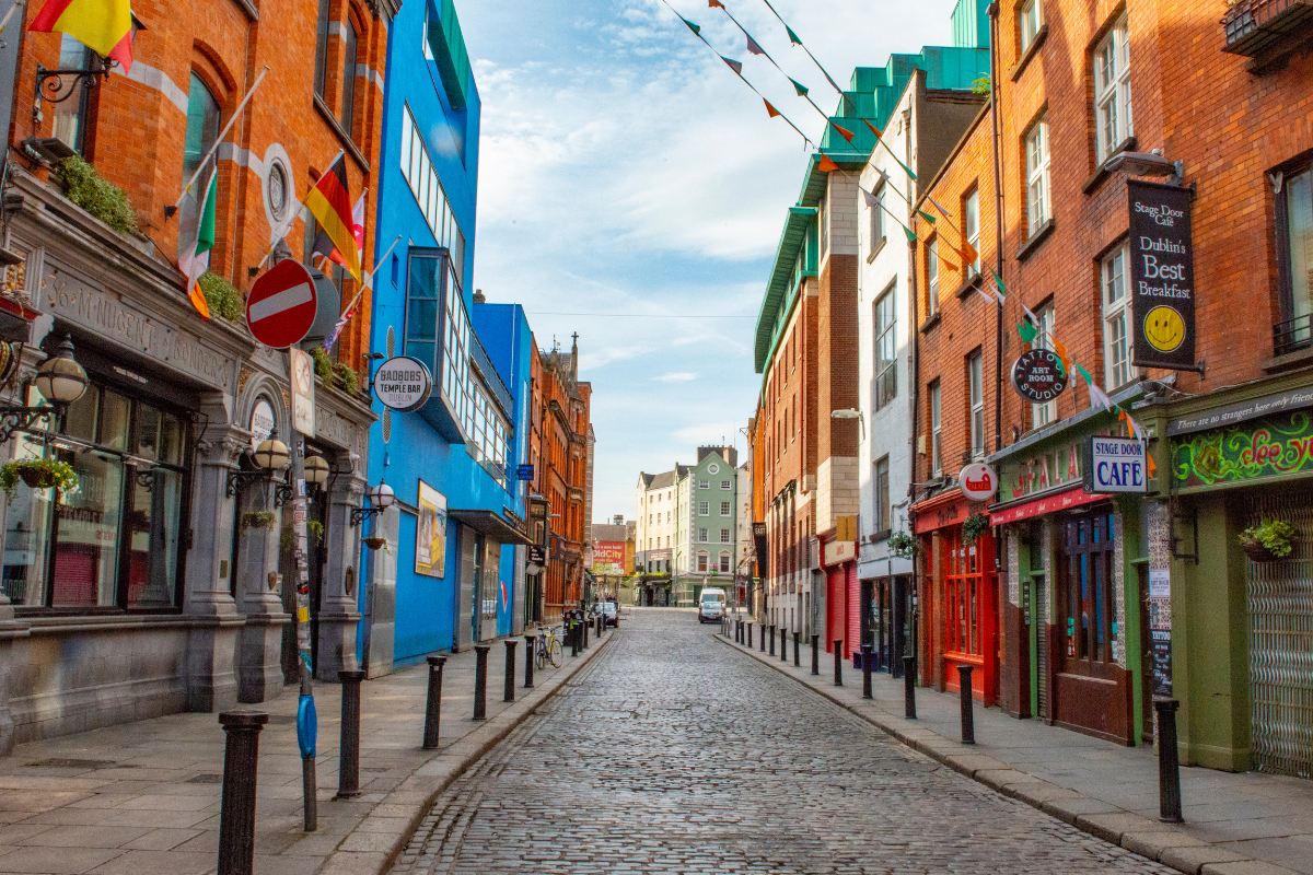 A cobblestone street in Dublin, Ireland, lined with colorful buildings housing shops and cafes 