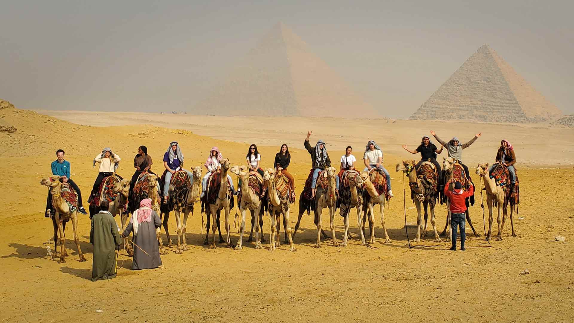 St. Thomas students riding camels in front of pyramids in Egypt