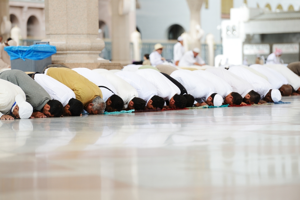 A group of muslim men praying with heads bowed to the ground
