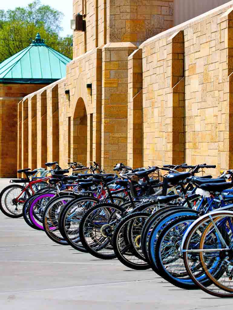 A student rides his bike away from a rack full of bikes outside O'Shaughnessy Stadium.