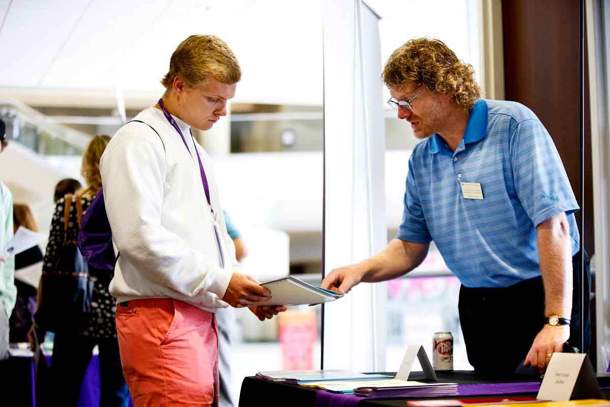 A student speaks with an accounting professor at a campus event.