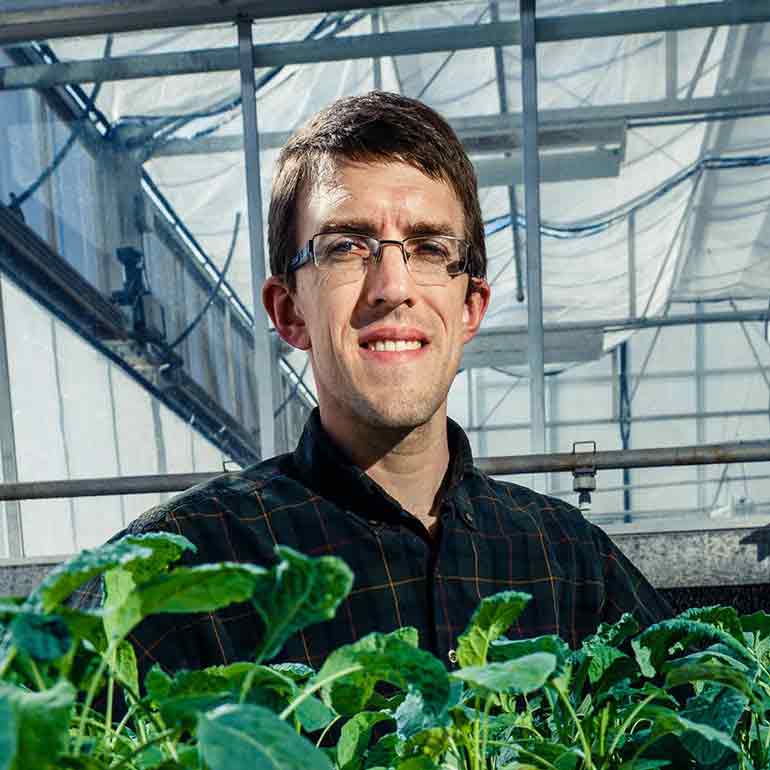 Biology professor Gaston "Chip" Small poses near his aquaponics experiment in the Owens Science Hall Greenhouse.