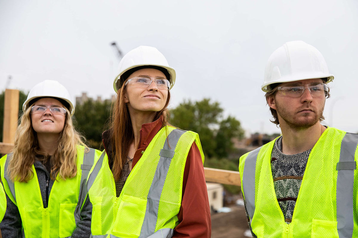Three students look on while at an active construction site.