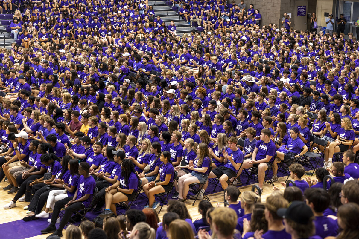 large group of students in purple shirts seated in an auditorium