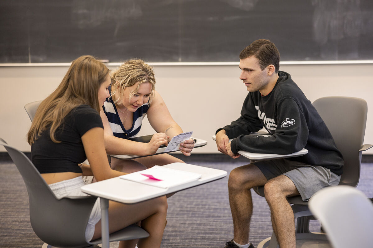 three seated students intensely discuss a project