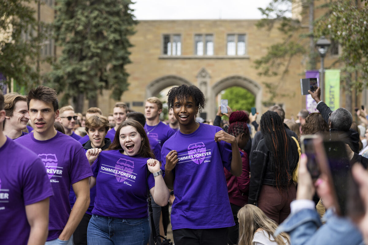 students wearing purple shirts walk through arches
