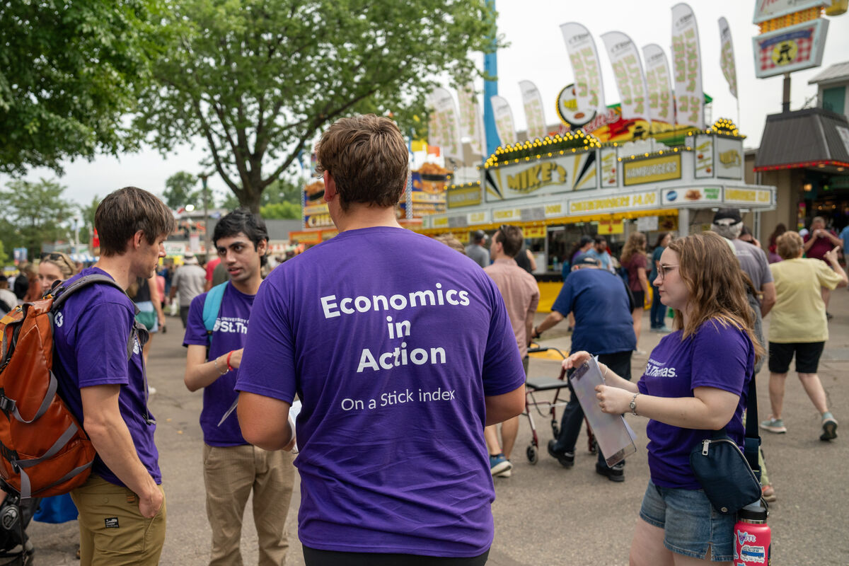 students conduct surveys at the state fair wearing shirts saying "economics in action"