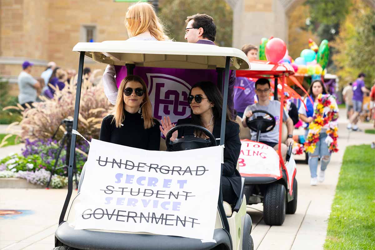 USG students riding golf cart during homecoming parade