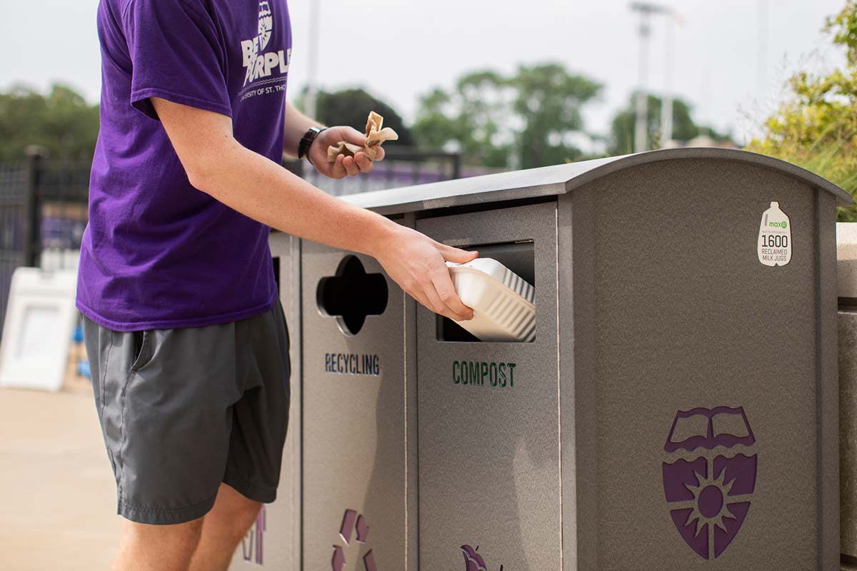 Student places trash in recycle bin on campus