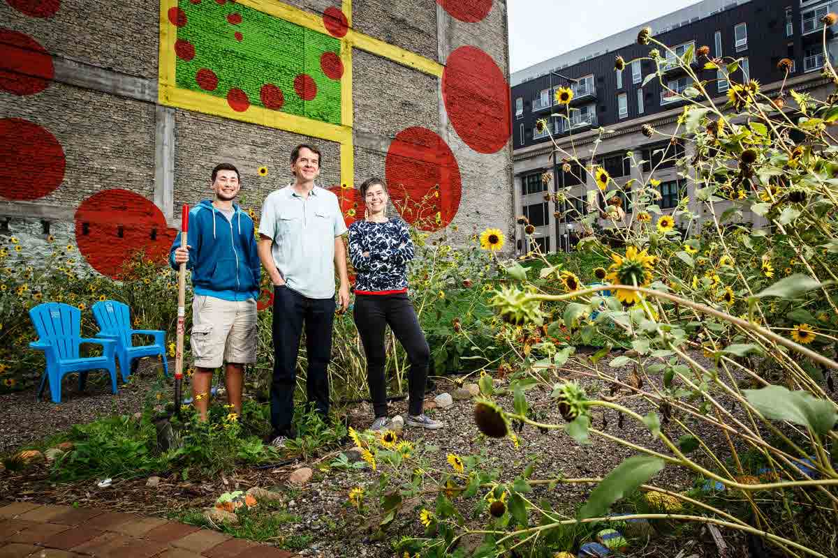 professor and student stand outside in a garden with sunflowers