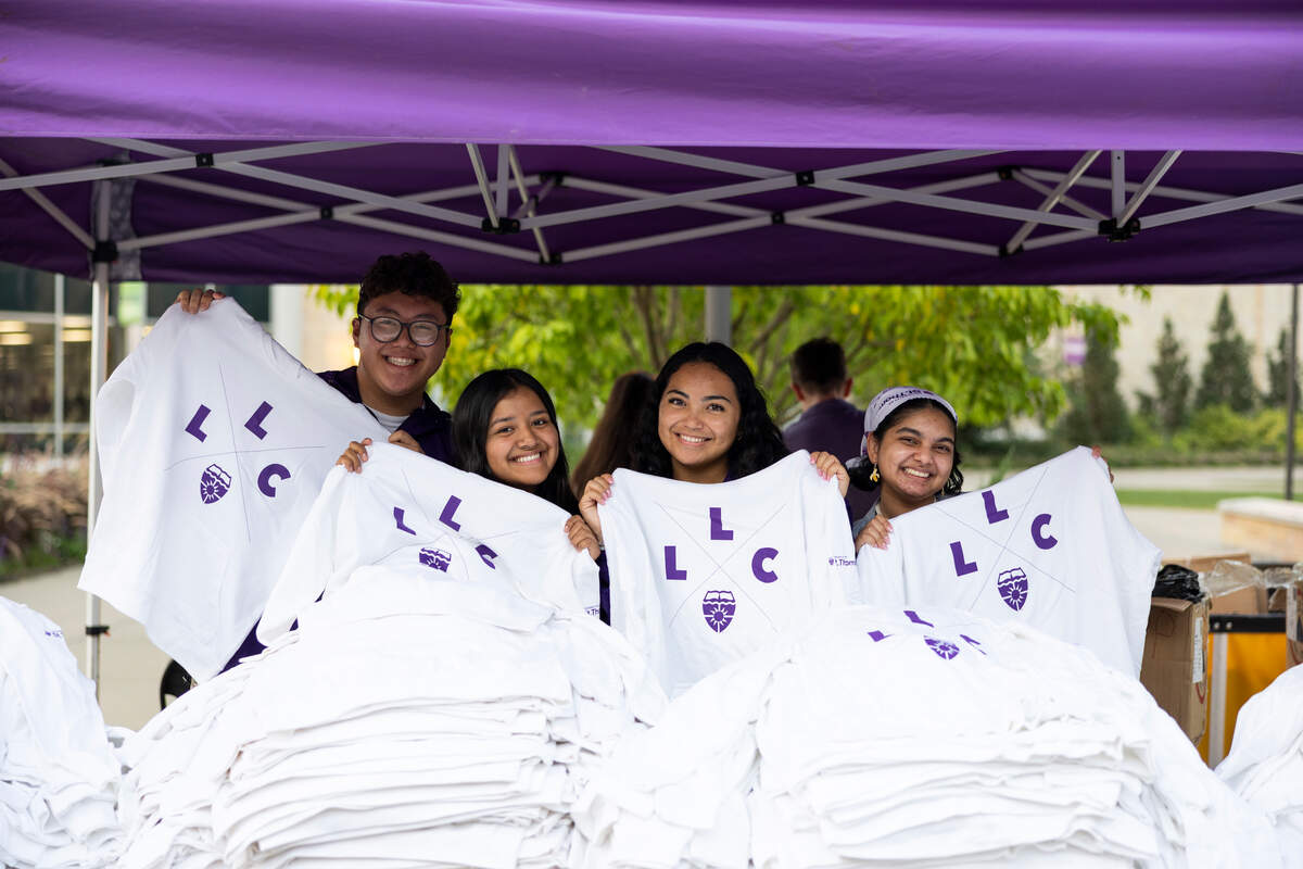 Students hold up LLC T-shirts