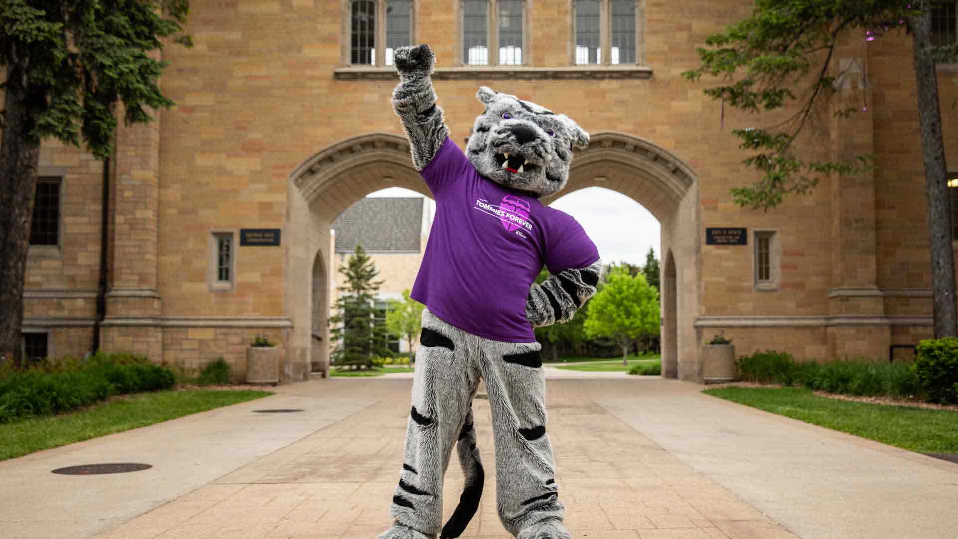 tommie mascot stands in front of the arches