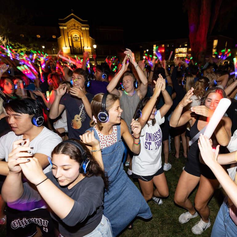 Students dancing at headphone disco at night