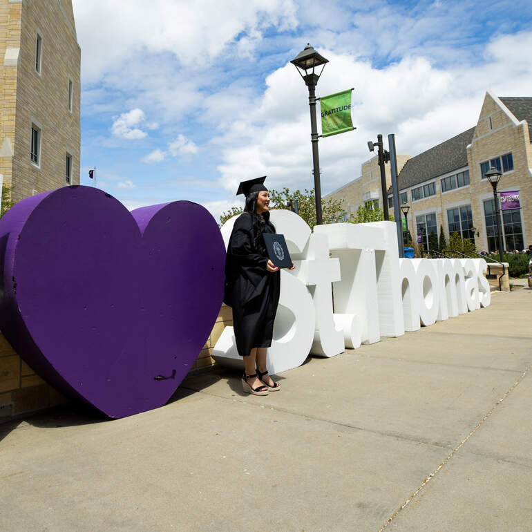 Graduate posing next to giant letters