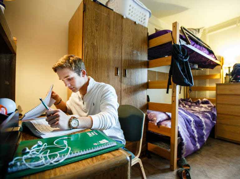 student at desk with bunkbeds behind