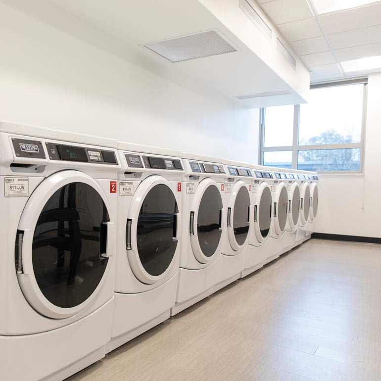 Laundry room with a row of washers and dryers.
