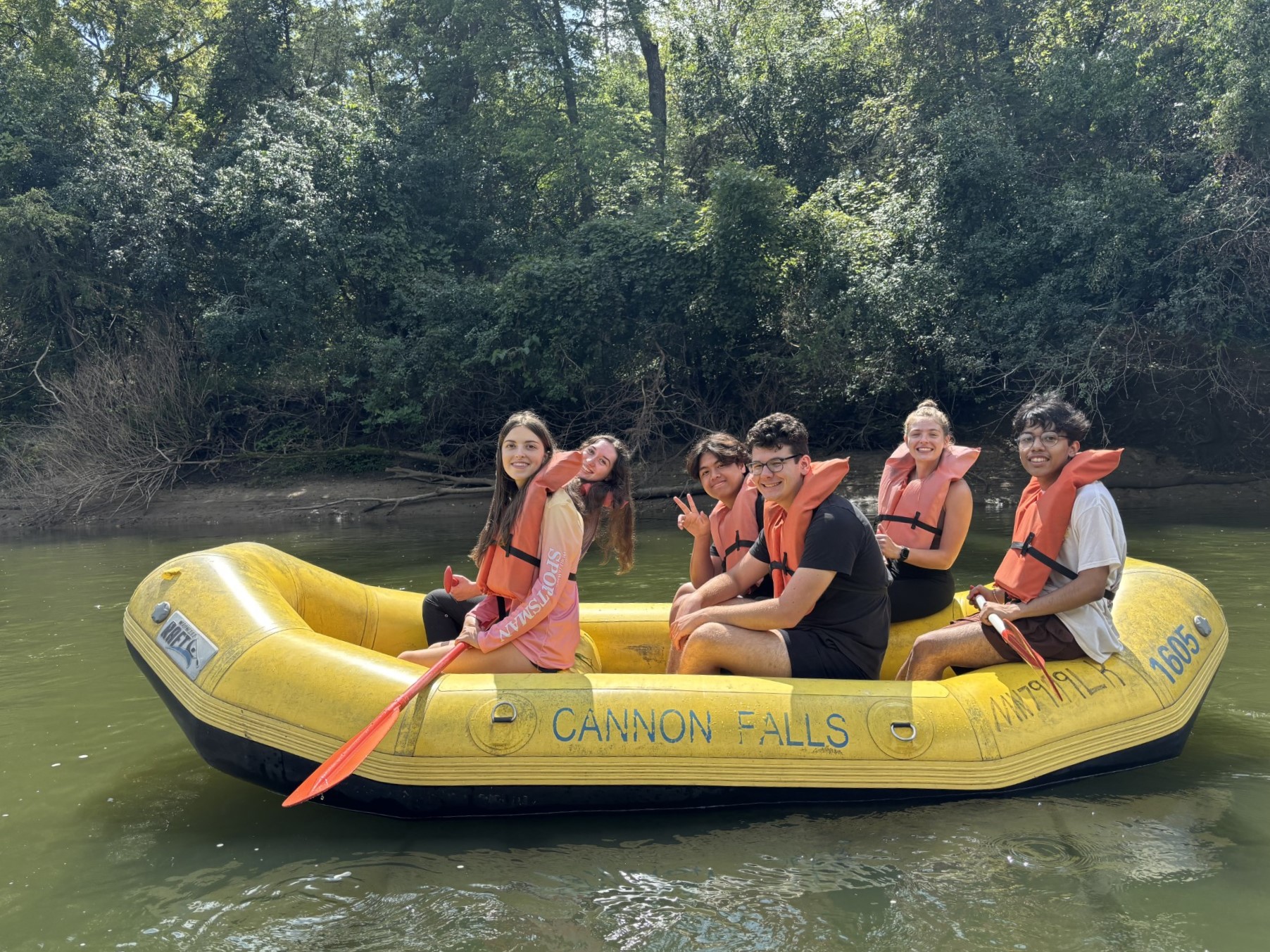 Four students take research notes in front of a river