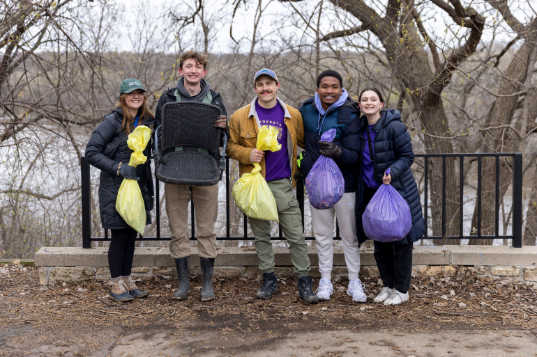 Students standing by river with trash bags