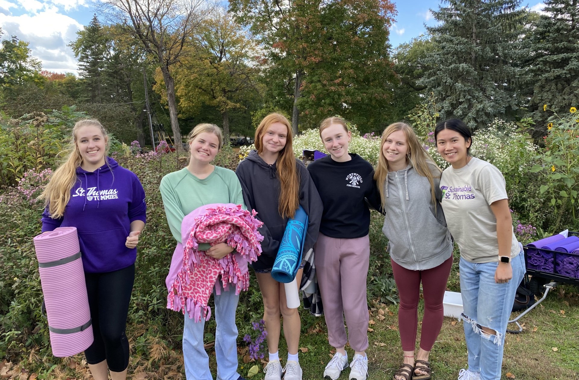 Students stand holding clothes during a clothing swap.