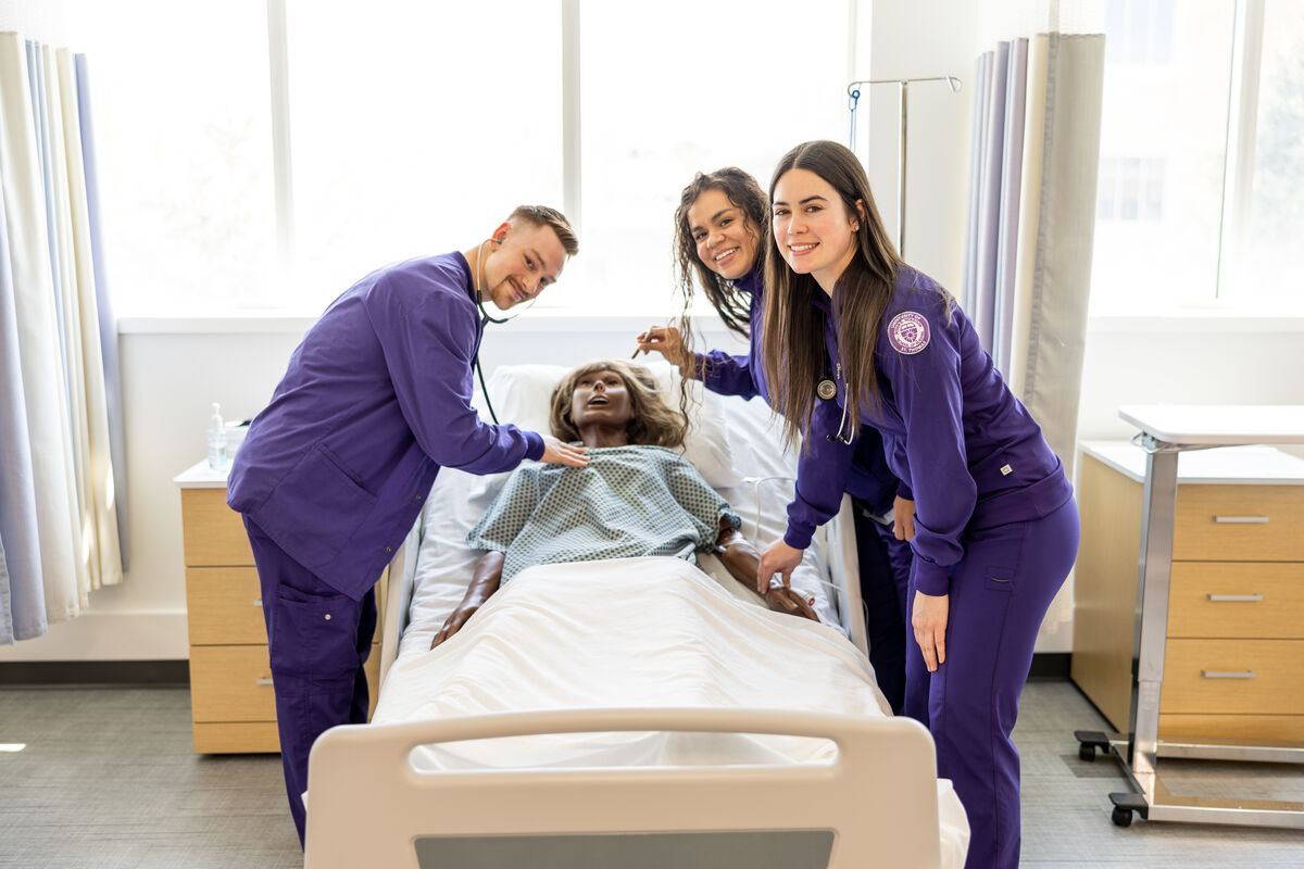 Nursing students stand with a fake patient