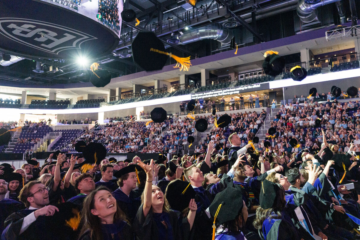Graduates toss their caps in the air during graduation commencement