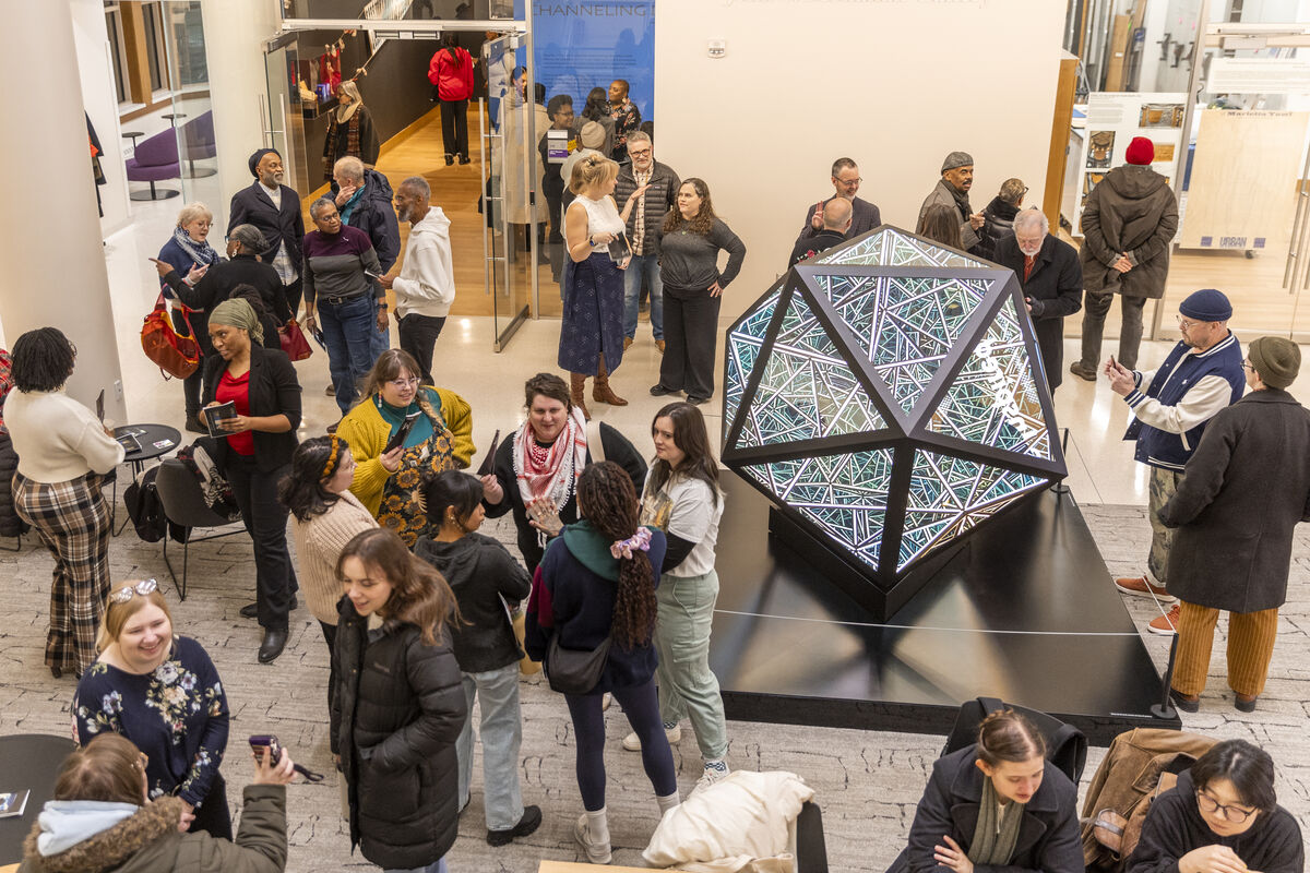 A crowd stands near the Portal Icosahedron sculpture in the Schoenecker Center