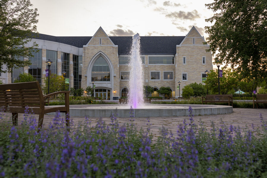 Purple flowers in the foreground with Anderson Student Center and fountain in the background.